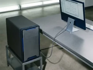 Dedizierter Server-Tower und Büro-Workstation durch Air-Gap getrennt, verbunden durch ein einzelnes Displaykabel auf grauem Schreibtisch.